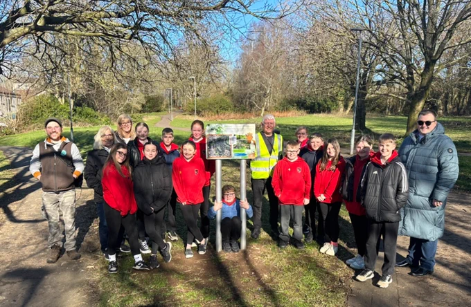 (Left) Ranger Andrew with Council Leader Marie Burns, Primary 7 class from St John Ogilvie Primary School and Cllr Nairn McDonald (right) at welcome sign of new Bourtreehill Park Woodland Trail.

