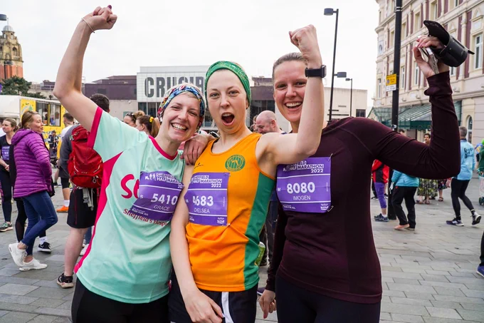 Three Sheffield Half Marathon runners standing together smiling and cheering. 