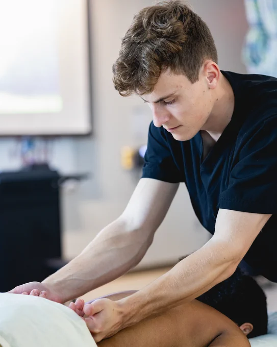 A physical therapist concentrating while working on a patient's back. 