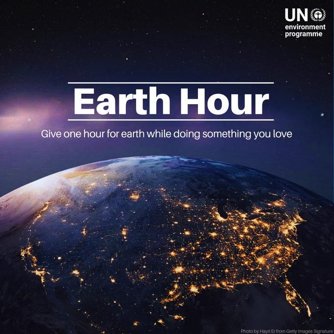 A digital image of Earth from space at night shows city lights illuminating the continents. The text "Earth Hour" is prominently displayed in bold white letters, with a subtitle reading, "Give one hour for Earth while doing something you love." The image is credited to Hayri Er from Getty Images Signature.