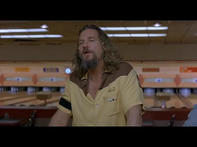 The camera has zoomed out slightly as the Dude stands up to leave the bar.
