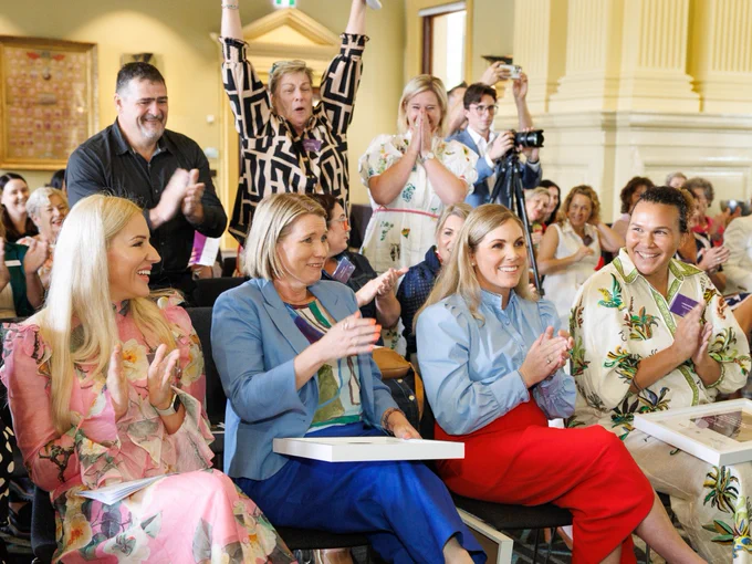 Audience members enthusiastically clapping during an indoor event.