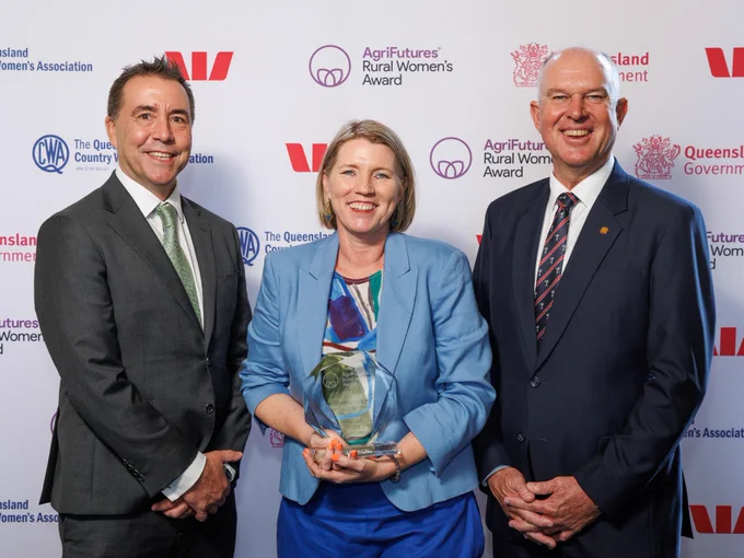 Three individuals posing with an award at an event sponsored by AgriFutures and Queensland Government. The person in the center is holding a glass trophy. They are standing in front of a backdrop with logos of the sponsoring organizations.