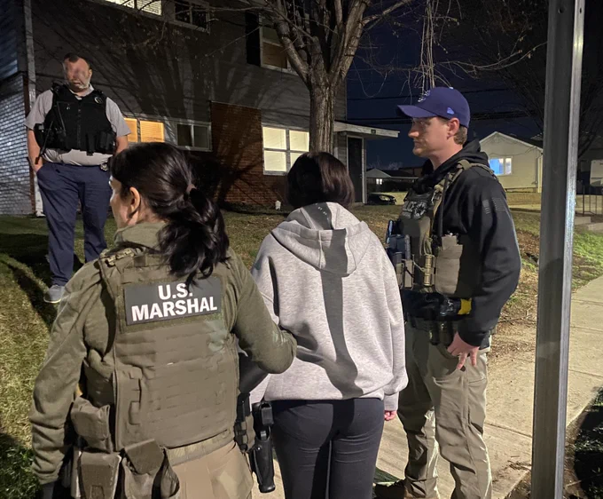 Two Deputy U.S. Marshals stand with a recently recovered critically-missing child. 

Note: One local law enforcement officer's face has been blurred out for operational purposes.