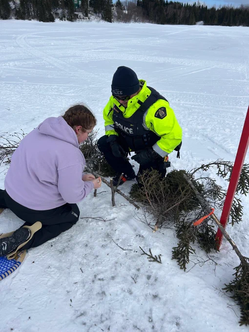 A uniformed police officer watching a student show off her outdoor skills.