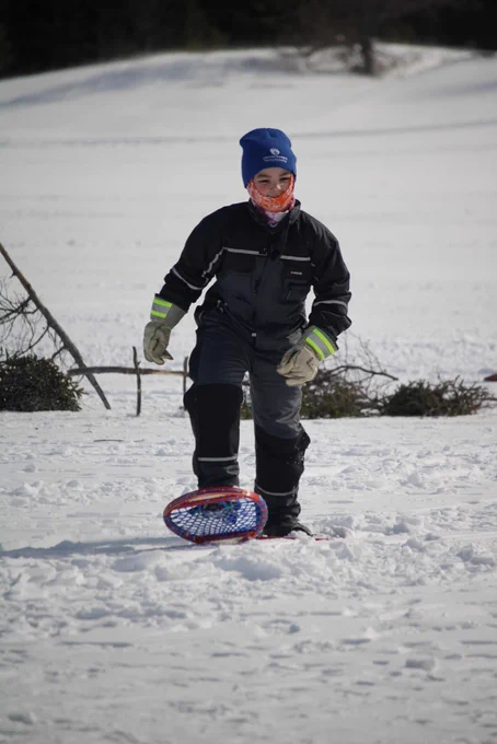 A student walking with snowshoes. 