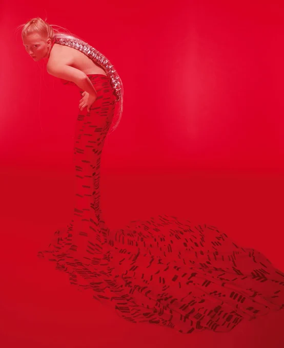 Woman in red dress with long train against a red backdrop