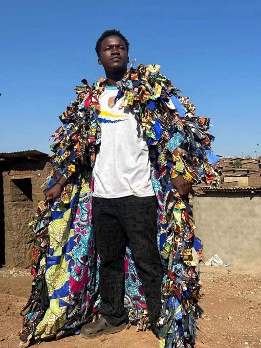 A person wearing an embellished coat made from scraps;