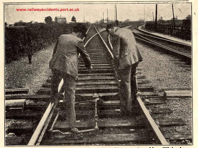 Posed staff safety photograph, showing two railwaymen looking at a pair of points, with their backs to oncoming traffic, risking being run down.