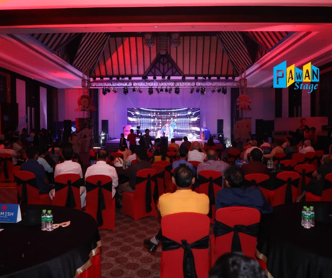  A spacious ballroom arranged with tables and chairs, decorated for a corporate dealer meet party at a Udaipur resort.