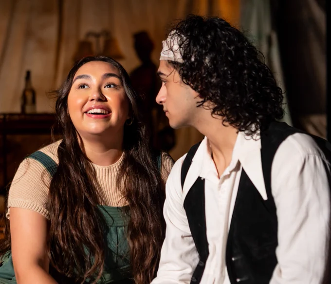 Two actors perform in a scene together, one looking forward excitedly