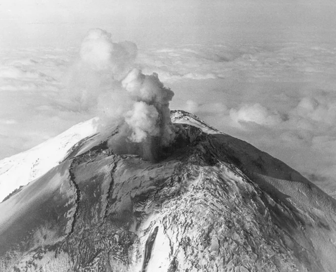 Aerial view of a small plume of steam (white) and light ash (gray) erupting from the summit of Mount St. Helens on April 7, 1980. Photo by R. Waitt.