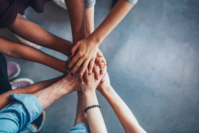Stock image of group of people joining hands together.
