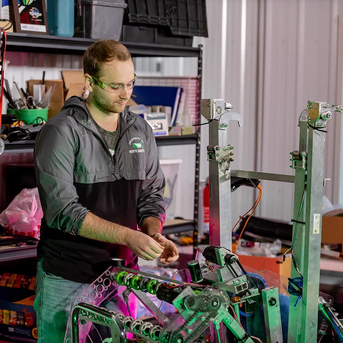 A student works with his hands on a robot inside of a UND engineeirng lab.