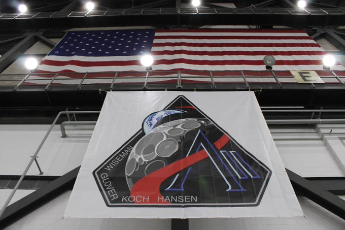 The new Artemis II mission patch banner hangs in the Vehicle Assembly Building transfer aisle. An american flag hangs above it.