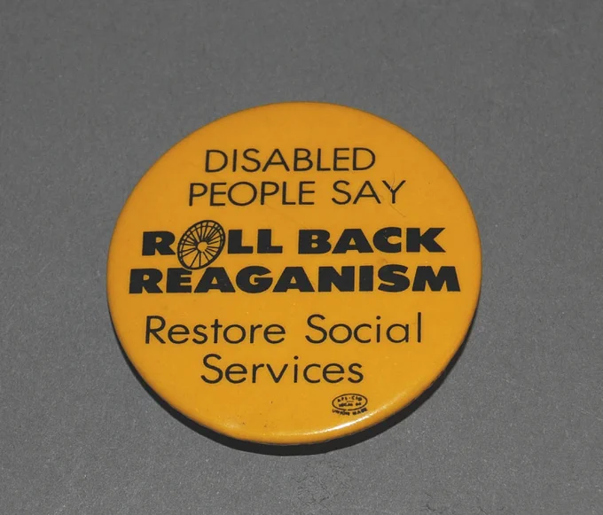 Yellow badge saying "Disabled people say roll back Reaganism, Restore social services"