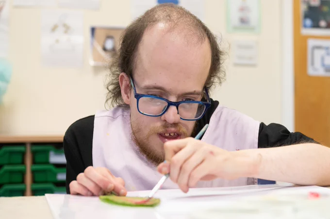 A male service user taking part in an art lesson.