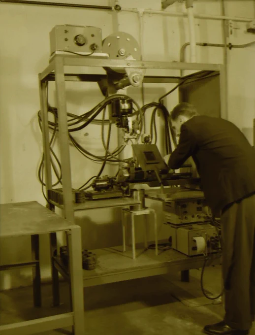 A man leaning over some equipment on shelving - equipment unknown.