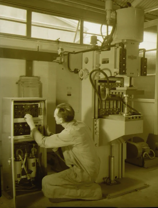 A man crouched on the floor working with equipment (unknown usage).