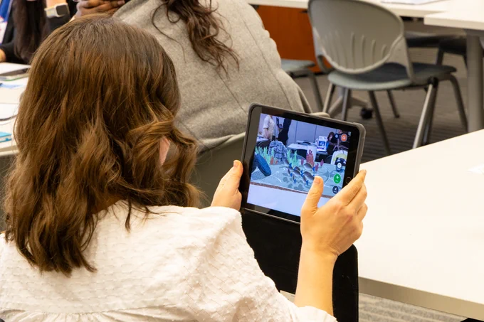 An educator exploring augmented reality environments on a tablet while seated at a table. 
