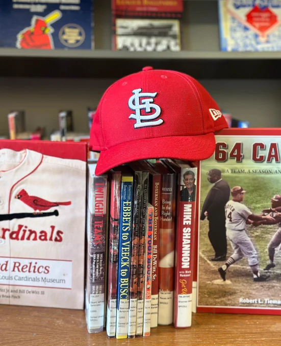 a stack of books on St. Louis Cardinals baseball with a red baseball cap