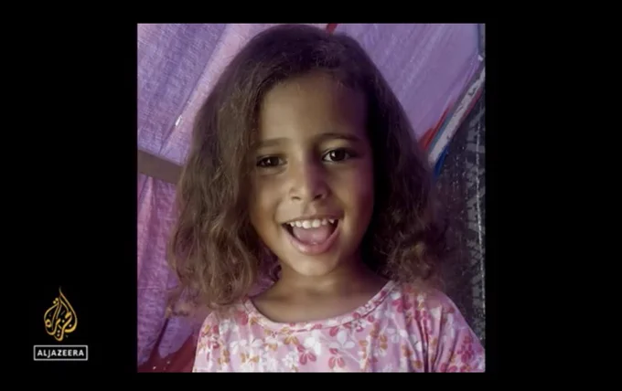 Screenshot from documentary linked in quoted tweet, showing Mira, a smiling young child with wavy brown hair and a pink flower patterned shirt