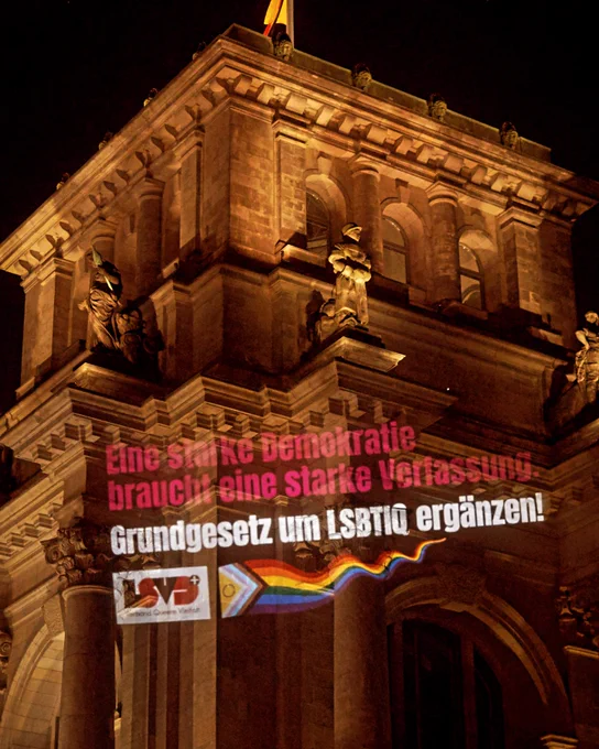 Foto. Lichtinstallation auf den Bundestag mit dem Text: Eine starke Demokratie braucht eine starke Verfassung. Grundgesetz um LSBTIQ ergänzen.