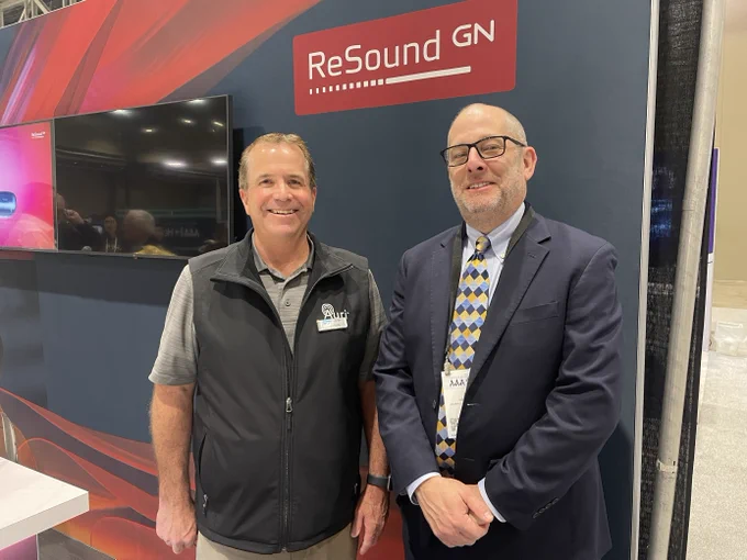 Hearing Loss Association of America (HLAA) Director of Public Policy Neil Snyder (r) with Listen Technologies Auri Product Manager Wayne Whiteley (l) in front of ReSound signage at the AAA2025 Conference, March 26, 2025.