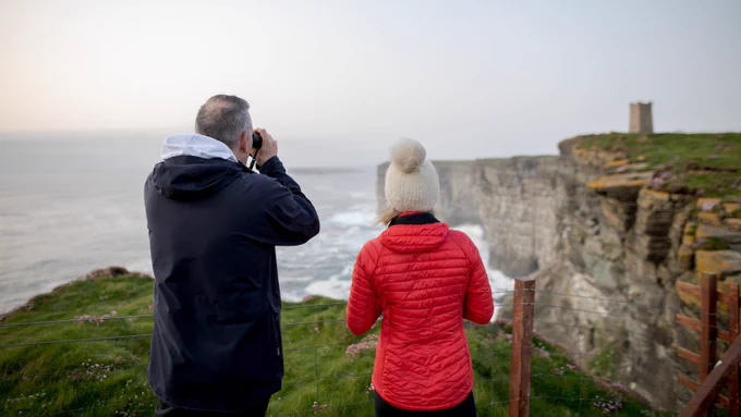 Couple birdwatching at RSPB Marwick Head, Orkney.