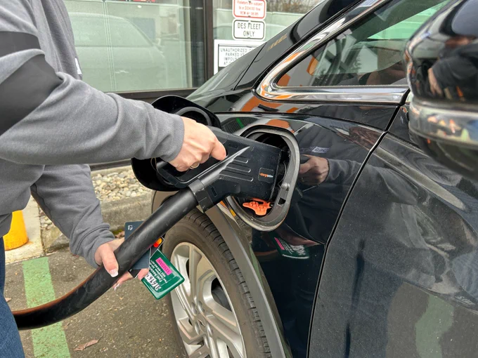 Person plugging in an electric vehicle charger into their car port.
