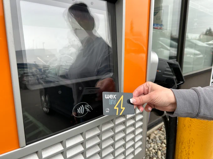 Person using tap to pay at an electric vehicle payment machine.