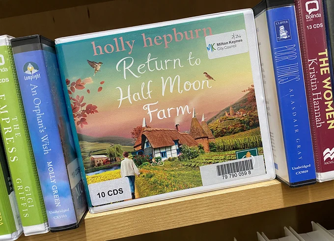 Audiobook titled "Return to Half Moon Farm" by Holly Hepburn, displayed on a library shelf among other audiobooks.