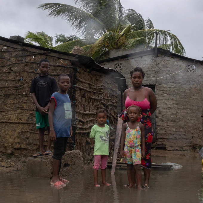 A family, a mother and her two girls and two boys, stand in front of their flooded house in Mozambique.