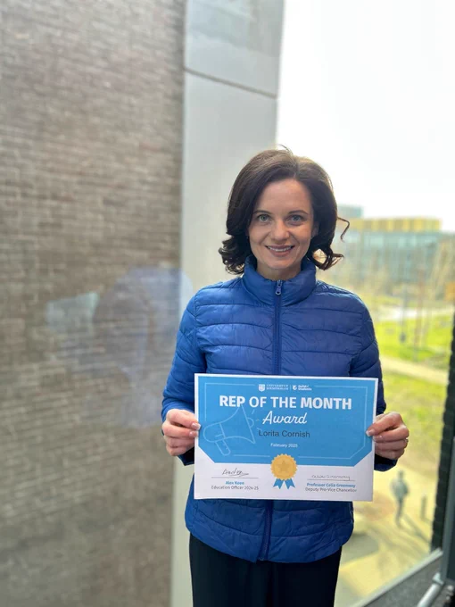 Image of a student smiling at the camera holding a certificate for Rep of the Month.