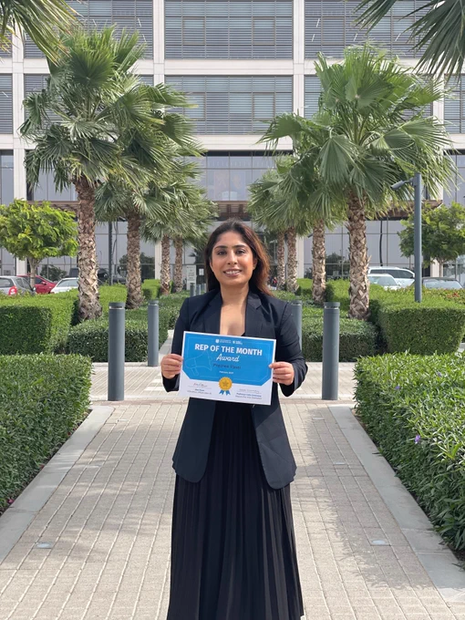 Image of a student from the Dubai campus smiling at the camera holding a certificate for Rep of the Month.