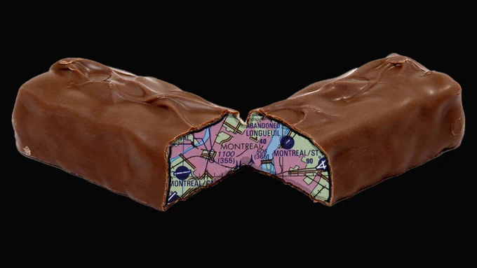 A chocolate candy bar split in the middle, with a map as the filling. (Photo Credit: PIXY#ORG; U.S. Defense Mapping Agency Aerospace Center Tactical Pilotage Chart from the Perry-Castañeda Library (PCL) Map Collection; and composite by the Army Geospatial Center)