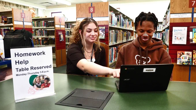 Staff helping a teen with homework at the Library.