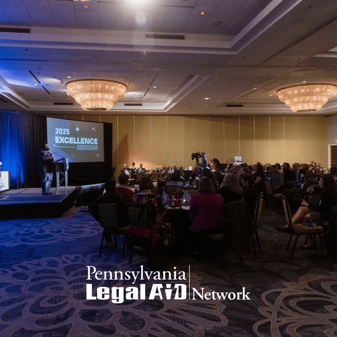 This is a photograph of the Pennsylvania Legal Aid Network 2025 Excellence Awards ceremony, held at the Hilton Harrisburg on March 27, 2025. The image shows keynote speaker, House Appropriations Chairman Jordan A. Harris, as he stands at a podium on stage addressing the room. Attendees are seated at round tables in a ballroom with chandeliers and '2025 EXCELLENCE AWARDS' is displayed on a screen behind them. The Pennsylvania Legal Aid Network logo appears at the bottom of the picture.