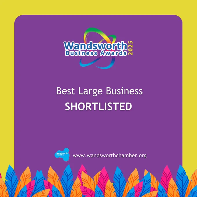 Promotional graphic for the Wandsworth Business Awards, featuring the award logo and text 'Best Large Business Shortlisted' on a purple and yellow background, with a decorative border of colorful leaves. The website 'wandsworthchamber.org' is displayed at the bottom.