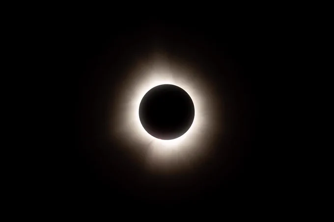 A photo of the total solar eclipse on April 8, 2024. The Moon completely blocks the Sun, so all that can be seen is a halo of light flaring outward. The rest of the sky is completely dark. Credit: NASA/Jordan Cochran