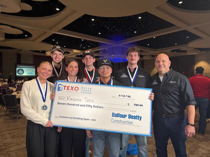 Photo of students and proffesor holding a check. 