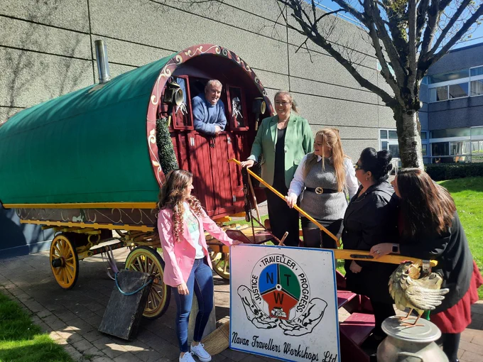 A traditional Traveller Wagon, with people standing on the outside and on the steps up to it