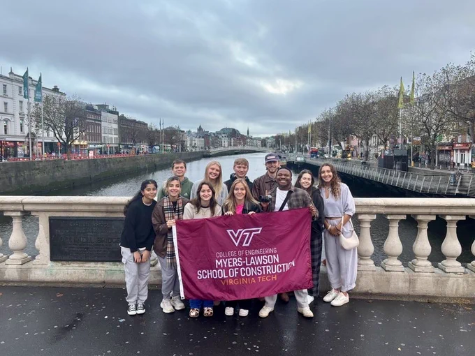 Photo of the team holding a Myers-Lawson flag on a bridge. 