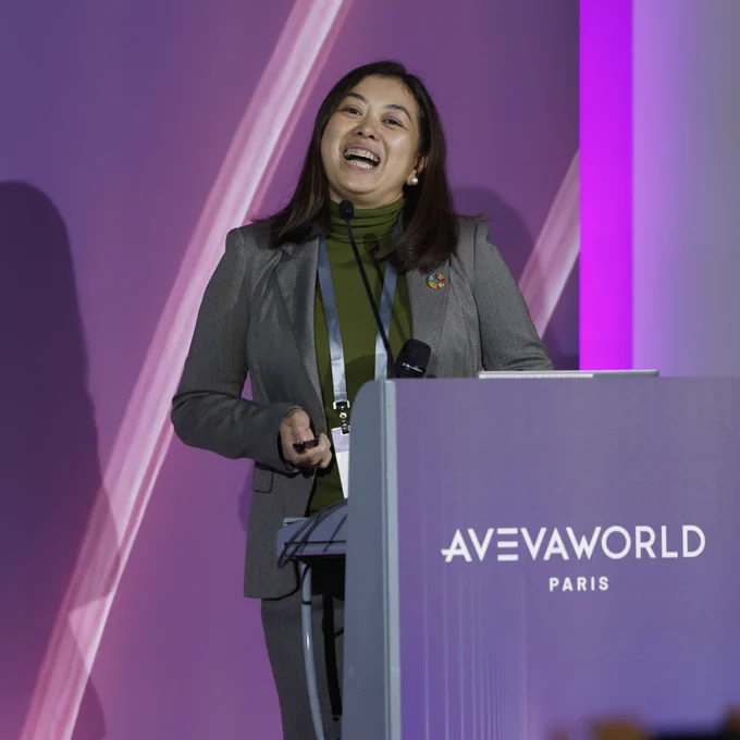 woman behind podium smiling in front a purple backdrop
