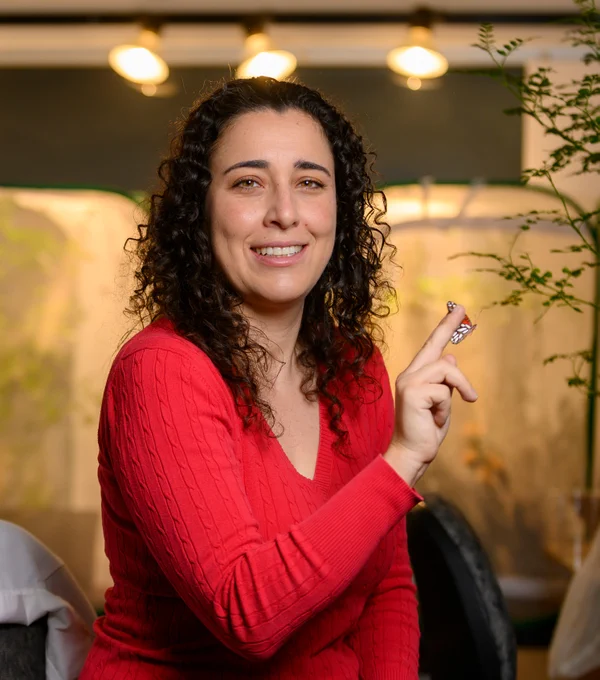 portrait of a person with curly dark hair and holding a butterfly and wearing a rich red shirt