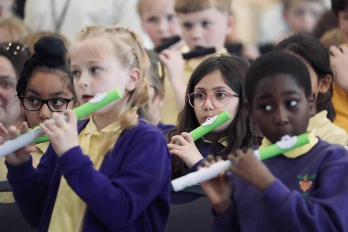 Children playing green musical flutes.