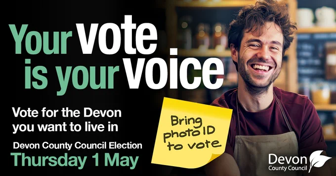 An image of a young man wearing an apron standing in a shop and smiling. To the left is a heading that says 'Your vote is your voice'. Under the heading it says 'Vote for the Devon you want to live in. Devon County Council Election Thursday 1 May.' Between the text and the image of the man is a yellow post-it note reminding people to bring photo ID. 