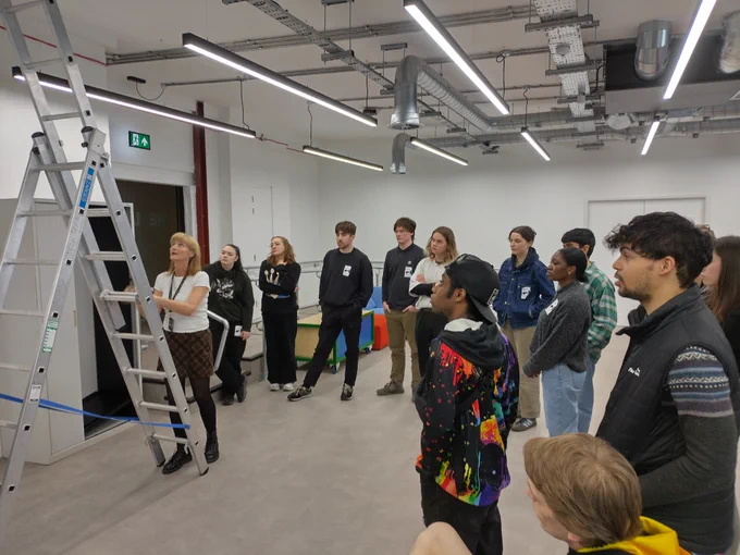 Creative Futures Get Into Event Production course. Young people people stood around a ladder learning safety guidelines when putting an event together. 