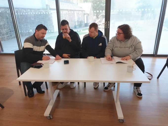 4 individuals sitting around a table, taking notes