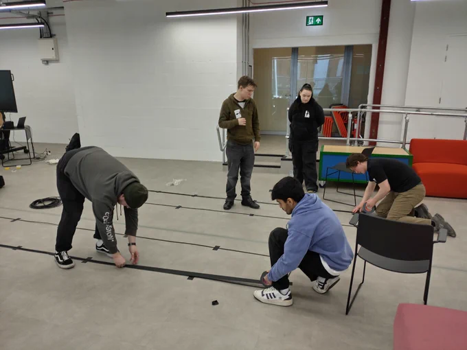 Creative Futures Get Into Event Production course. Young people people learning how to safely sellotape electrical wiring on the floor. 